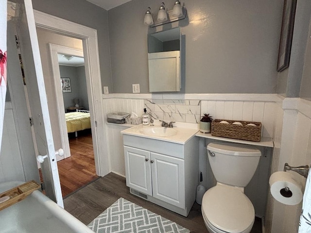 full bathroom with vanity, toilet, a wainscoted wall, and wood finished floors
