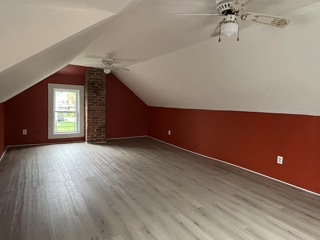 additional living space with ceiling fan, lofted ceiling, baseboards, and wood finished floors