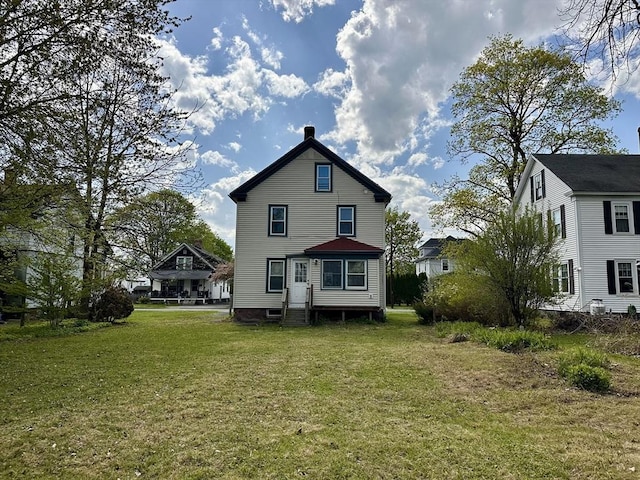 rear view of property featuring entry steps and a lawn