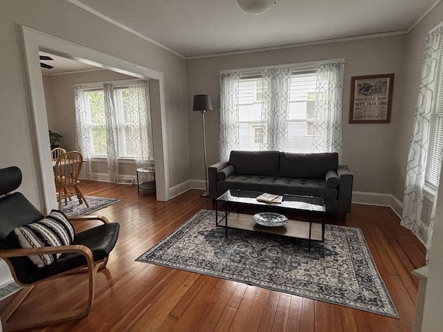 living room featuring baseboards, hardwood / wood-style floors, and crown molding