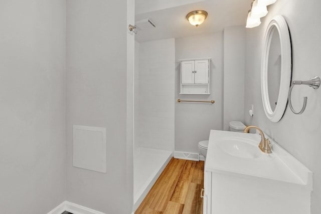 full bath featuring toilet, vanity, wood finished floors, baseboards, and walk in shower