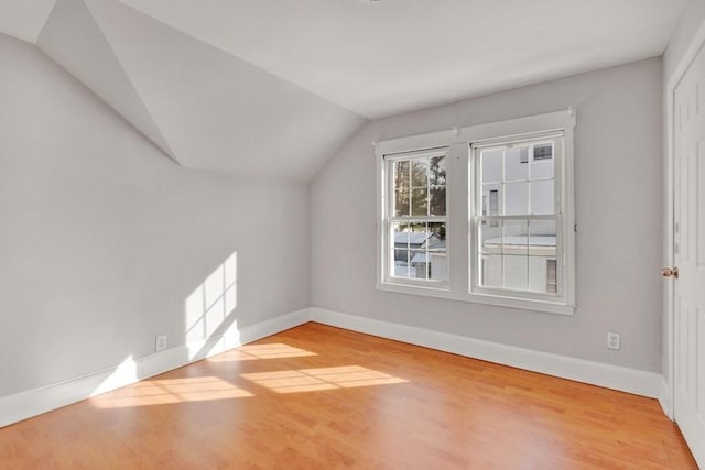 additional living space with baseboards, vaulted ceiling, and wood finished floors