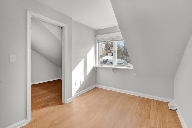 additional living space with baseboards and wood finished floors