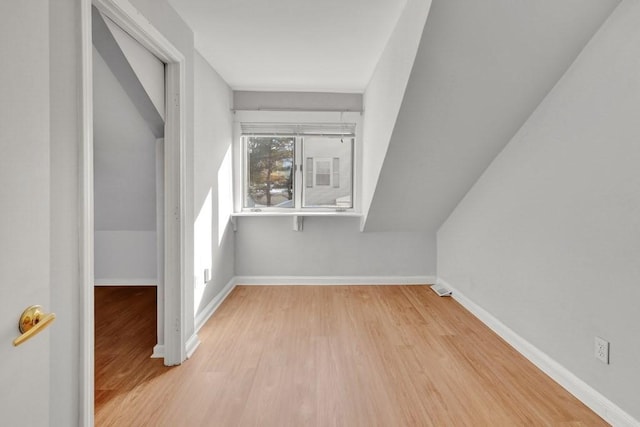 additional living space with light wood-style floors, lofted ceiling, and baseboards