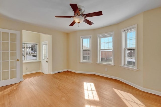 spare room featuring a ceiling fan, baseboards, and light wood finished floors