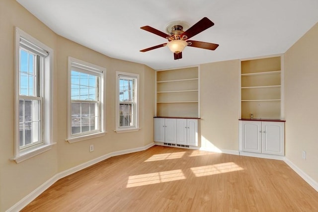 interior space featuring light wood-style floors, ceiling fan, built in shelves, and baseboards