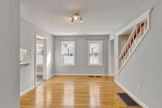 interior space with visible vents, light wood-style flooring, baseboards, and stairs