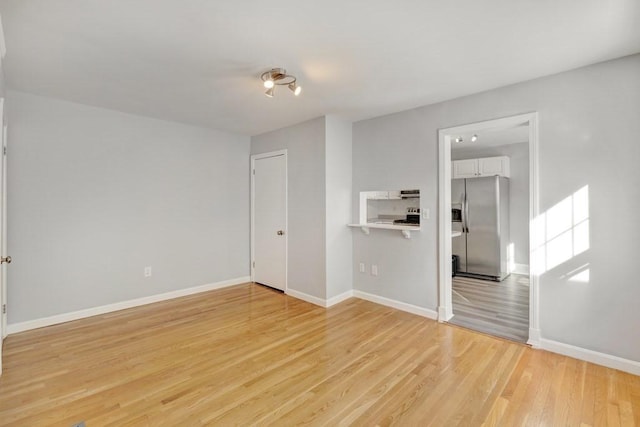 spare room with light wood-type flooring and baseboards