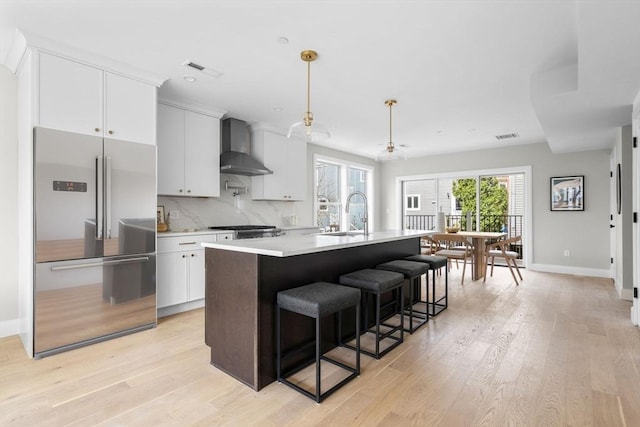 220 Bowen St Unit 2, Boston, MA 02127 - kitchen featuring high quality fridge, wall chimney range hood, a sink, a center island with sink, and light countertops