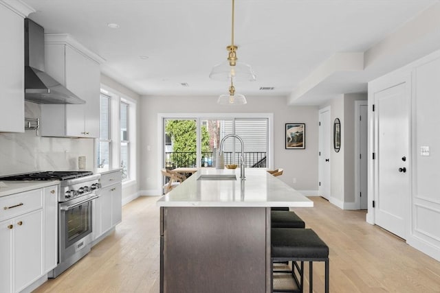 220 Bowen St Unit 2, Boston, MA 02127 - kitchen featuring stainless steel range, a sink, wall chimney range hood, a center island with sink, and baseboards