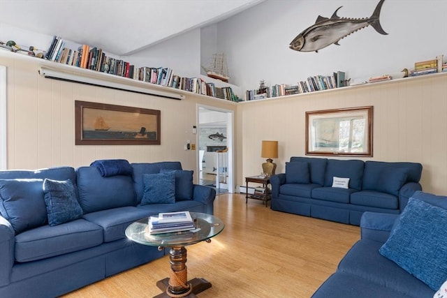 living area featuring a baseboard heating unit, vaulted ceiling, and wood finished floors