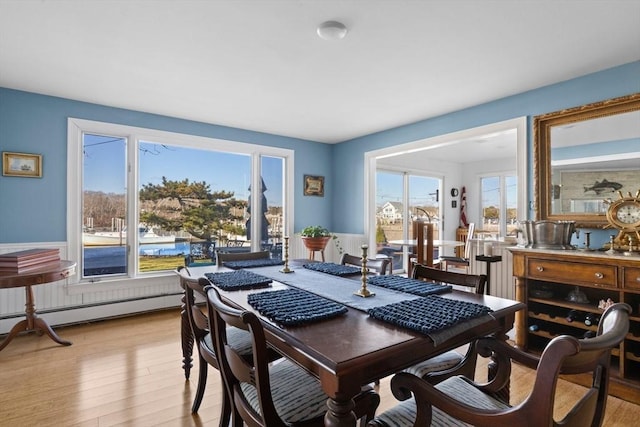 dining area with light wood-style flooring and a baseboard heating unit