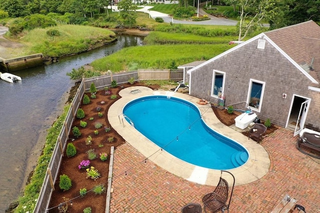 view of swimming pool with a patio area, a fenced in pool, a fenced backyard, and a water view