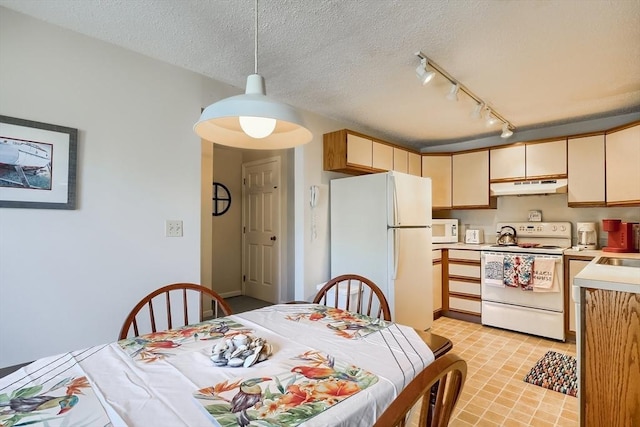 kitchen featuring sink, white appliances, hanging light fixtures, track lighting, and a textured ceiling