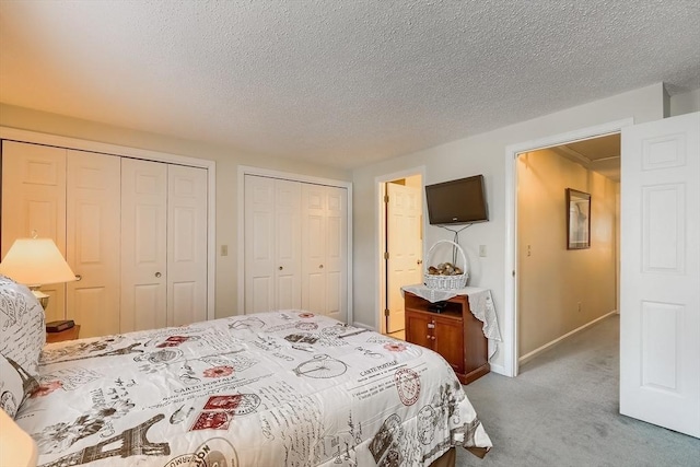 carpeted bedroom with a textured ceiling and two closets