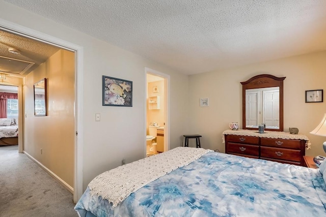 carpeted bedroom with ensuite bath and a textured ceiling