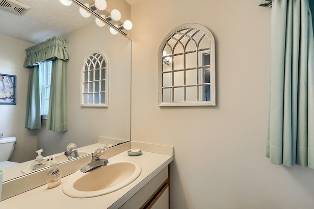 bathroom with vanity, a textured ceiling, and toilet