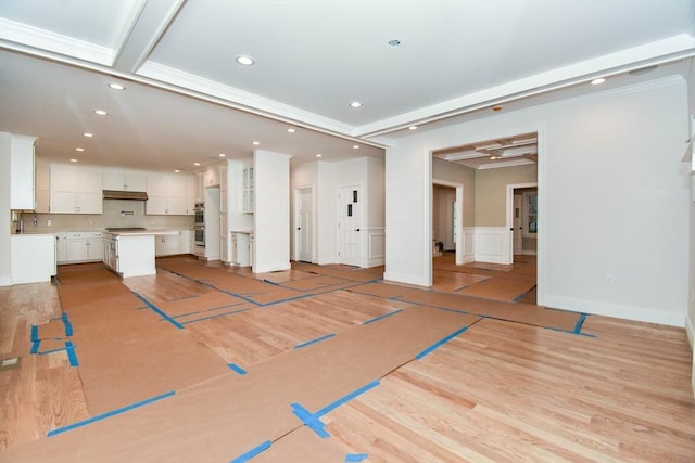 unfurnished living room with light wood finished floors, recessed lighting, ornamental molding, wainscoting, and baseboards