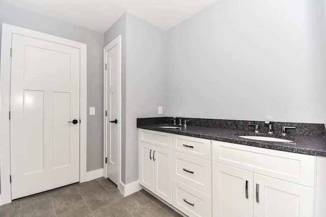 bathroom featuring baseboards, a sink, and tile patterned floors