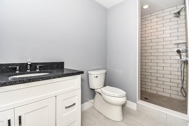 full bathroom featuring baseboards, a shower stall, toilet, and vanity