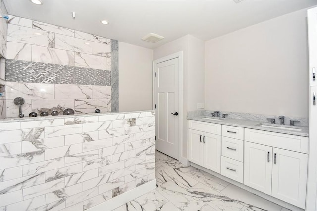 bathroom with marble finish floor, a walk in shower, a sink, and recessed lighting