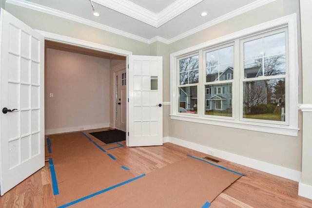 exercise area featuring baseboards, ornamental molding, and wood finished floors