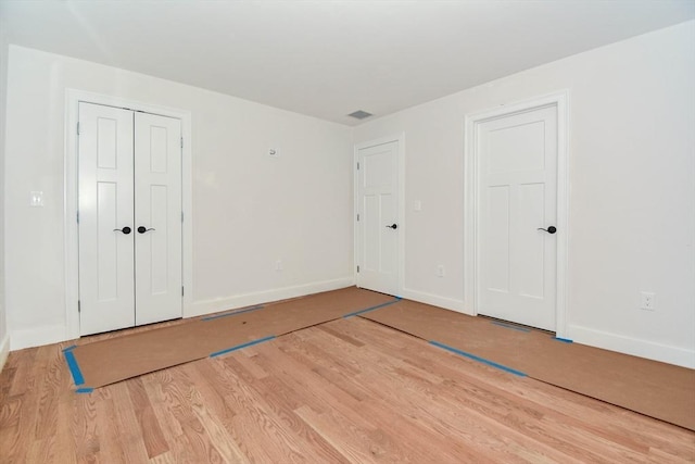 unfurnished bedroom with visible vents, baseboards, and wood finished floors