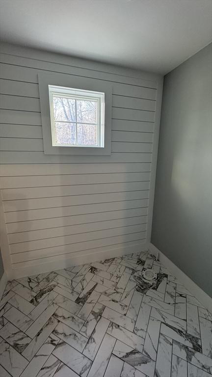 spare room with marble finish floor and wooden walls