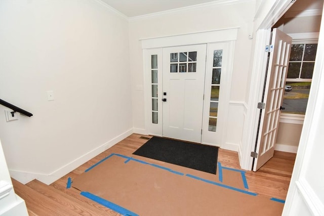 foyer entrance with ornamental molding, baseboards, and wood finished floors