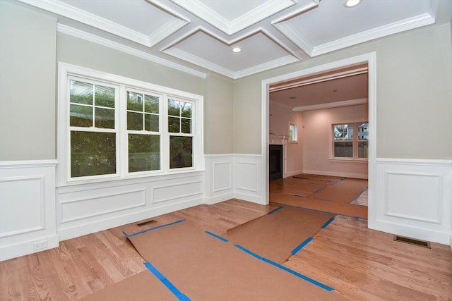 empty room featuring visible vents, coffered ceiling, ornamental molding, wood finished floors, and a fireplace