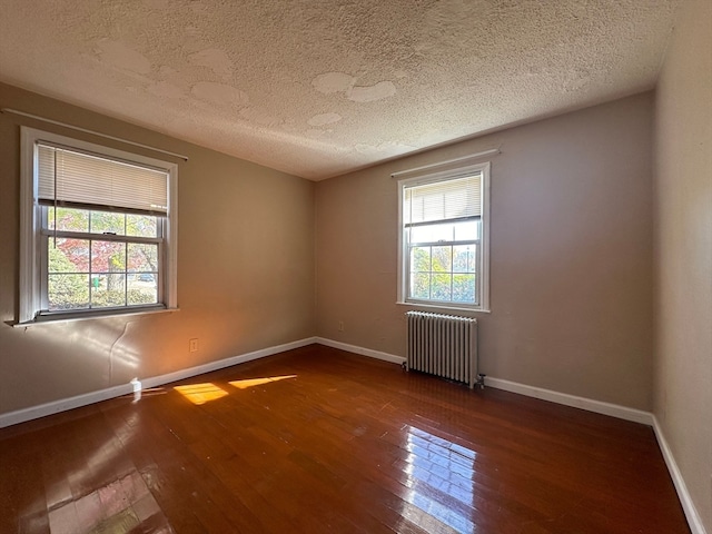 unfurnished room featuring dark wood-type flooring, a textured ceiling, and radiator