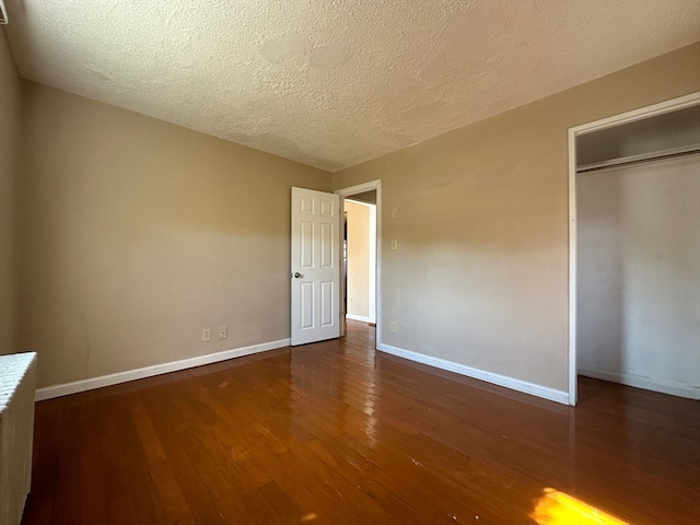 unfurnished bedroom featuring a textured ceiling, a closet, and dark hardwood / wood-style flooring