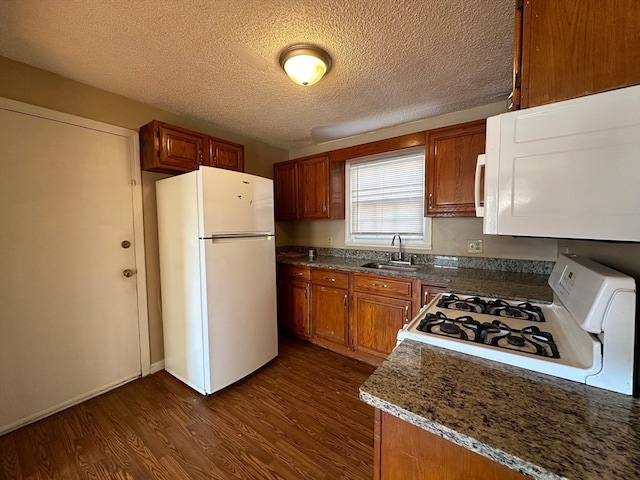 kitchen featuring sink, dark stone counters, dark hardwood / wood-style floors, a textured ceiling, and white appliances