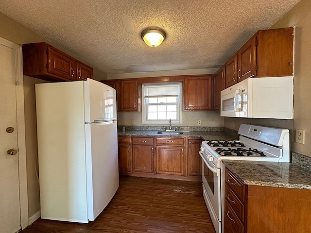 kitchen featuring white appliances, a textured ceiling, sink, and dark hardwood / wood-style flooring