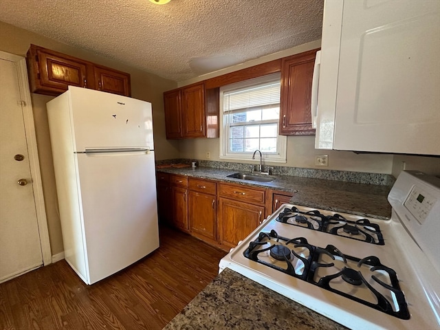 kitchen featuring dark wood-type flooring, white appliances, a textured ceiling, and sink