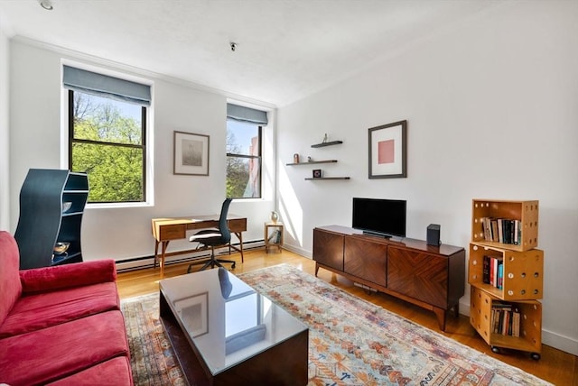 living area with crown molding, a baseboard radiator, and wood finished floors