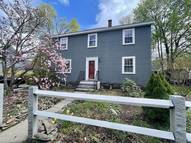 colonial home featuring a chimney and entry steps
