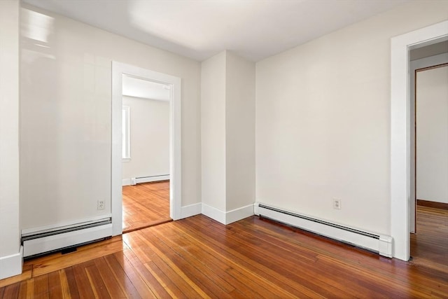 empty room featuring a baseboard heating unit, baseboards, hardwood / wood-style flooring, and a baseboard radiator