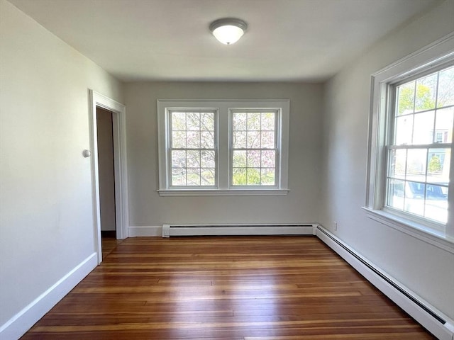 spare room with a wealth of natural light, wood finished floors, a baseboard heating unit, and baseboards