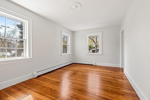 empty room with wood-type flooring, baseboard heating, and baseboards