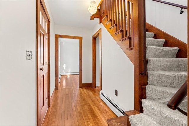stairs featuring hardwood / wood-style floors, baseboard heating, and baseboards