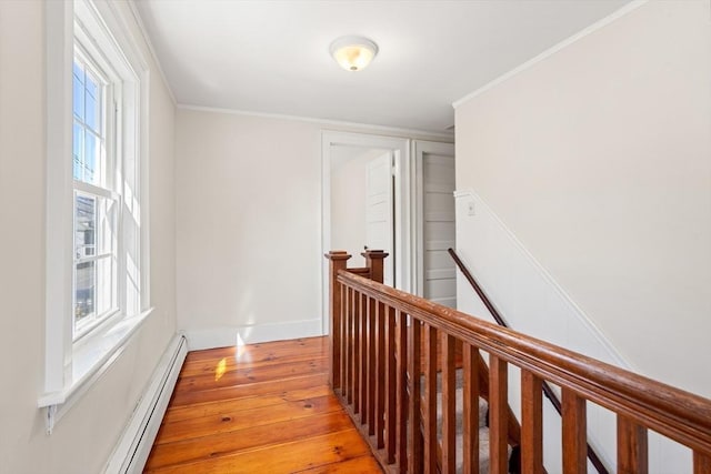 hallway with baseboards, an upstairs landing, light wood-style flooring, and a baseboard radiator