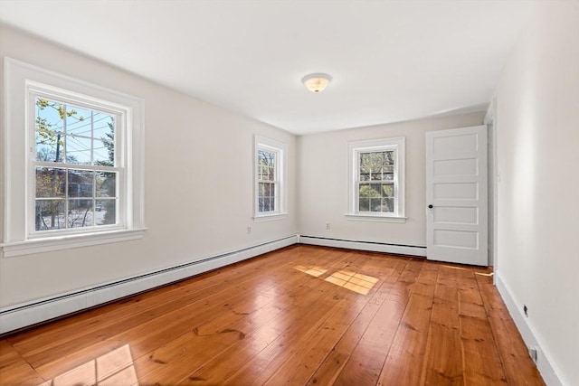 unfurnished room featuring light wood finished floors and baseboard heating
