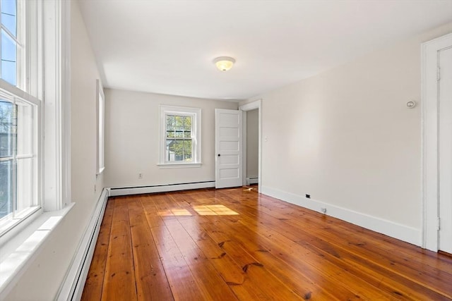 spare room with baseboard heating, baseboards, and hardwood / wood-style flooring