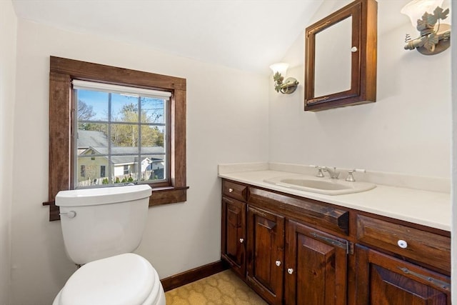 bathroom with toilet, lofted ceiling, vanity, and baseboards