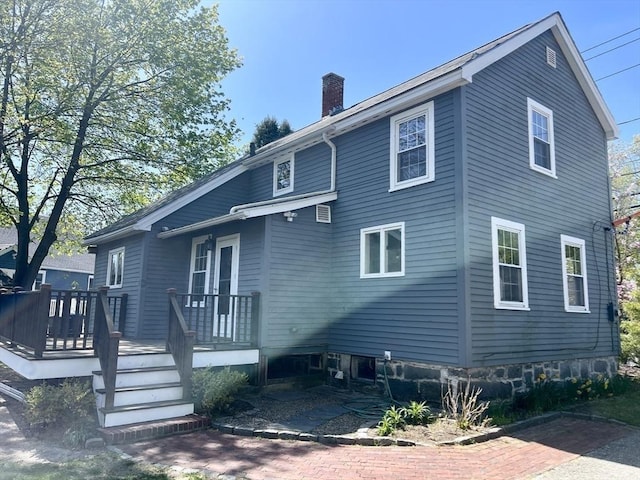 back of property with a chimney and a wooden deck