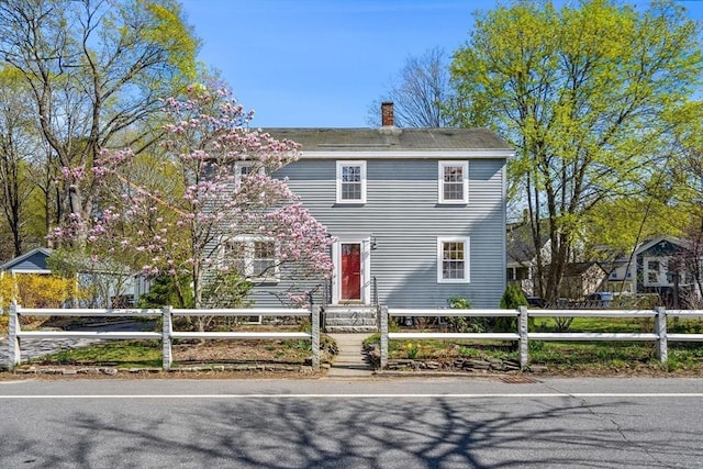colonial-style house with a fenced front yard and a chimney