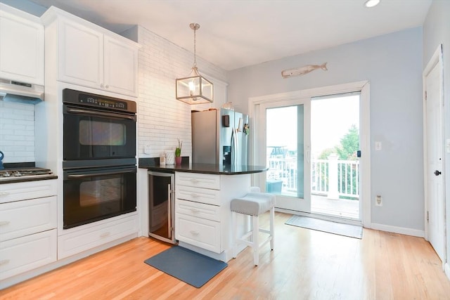 kitchen featuring hanging light fixtures, white cabinets, appliances with stainless steel finishes, and light hardwood / wood-style floors