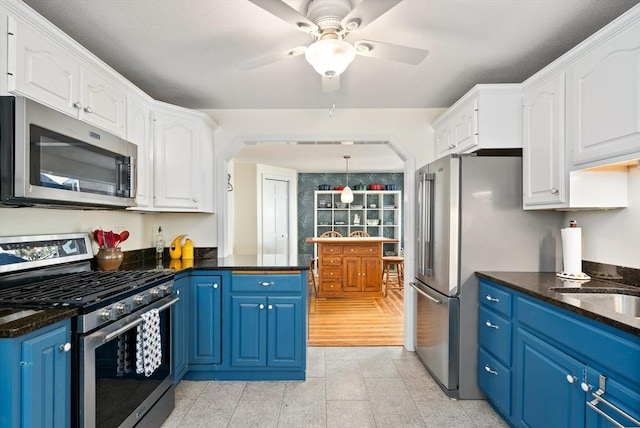 50 Walnut St, Northampton, MA 01060 - kitchen with stainless steel appliances, blue cabinets, white cabinets, a ceiling fan, and dark stone counters