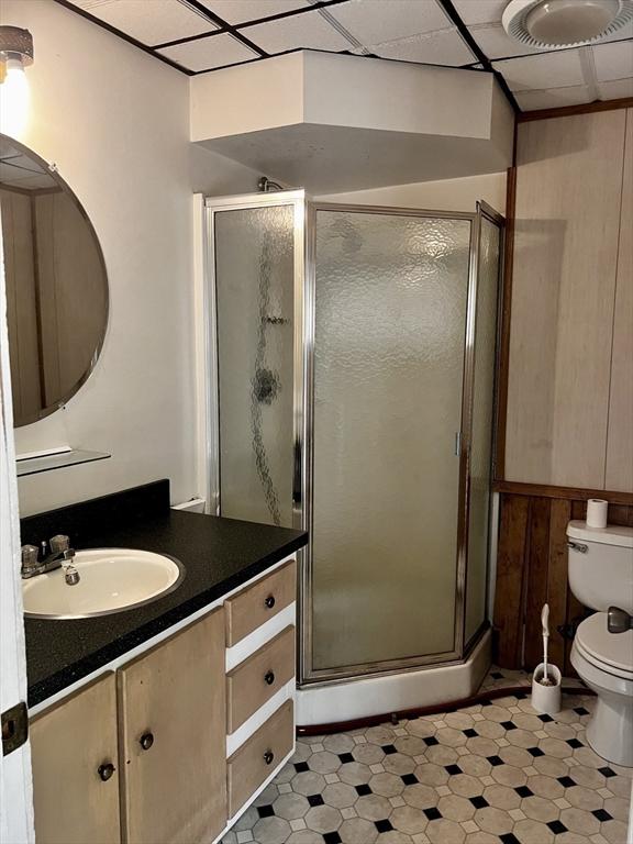 40 Papoose Lake Dr, Heath, MA 01346 - full bathroom featuring toilet, vanity, a shower stall, wooden walls, and tile patterned floors